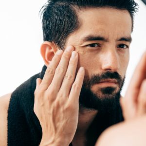 Man in front of mirrors looking at his wrinkles