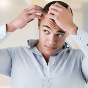 Man checking hairline in a bathroom